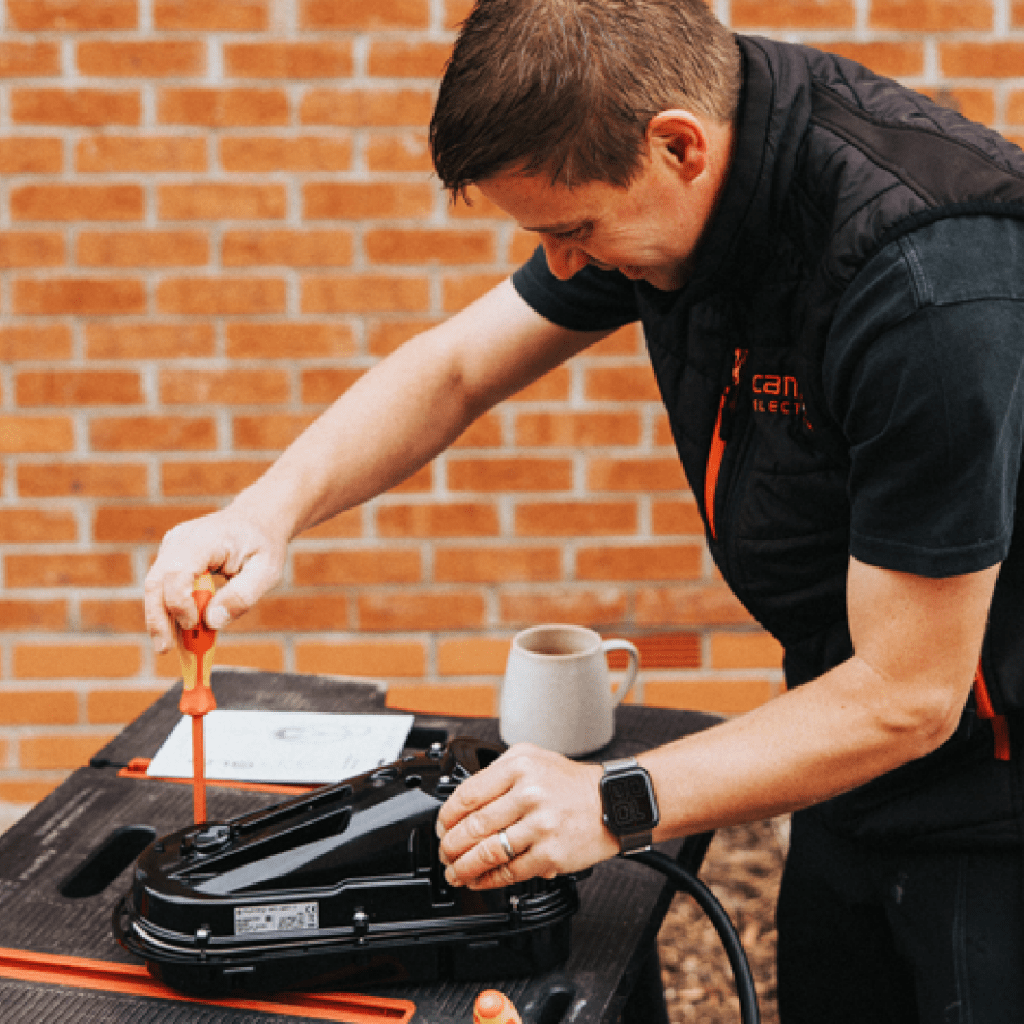 Person assembling electrical equipment outdoors.
